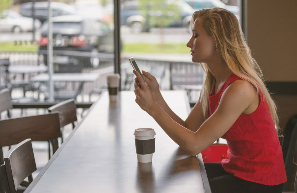 Woman creating event survey questions at coffee shop