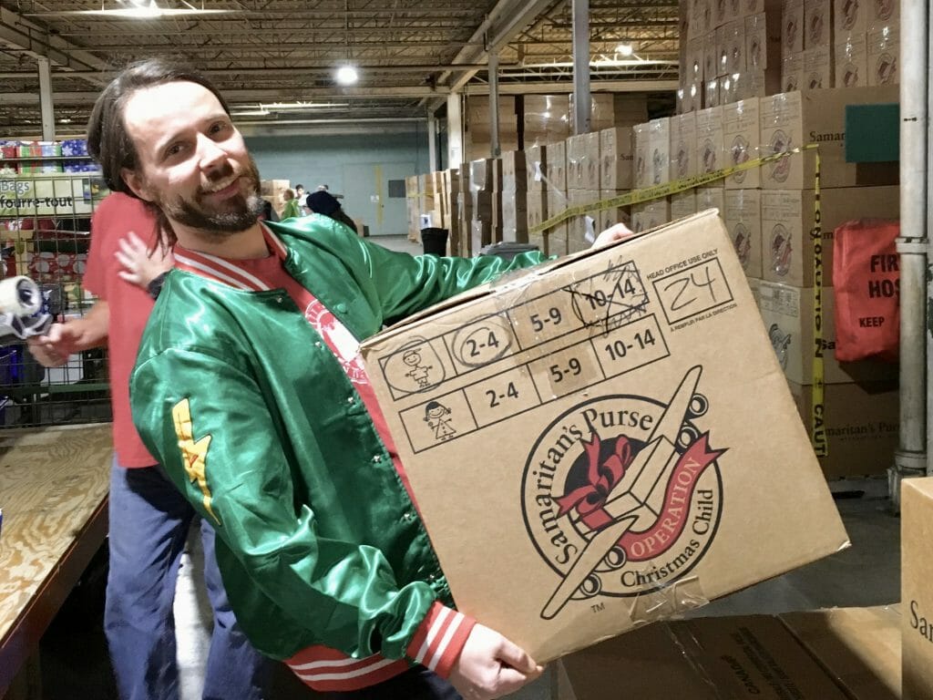 Adam lifts a box of gift shoeboxes onto a stack