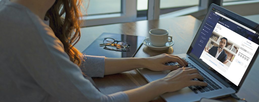 A woman watching a livestream during a virtual job fair on her laptop, indoors on a table