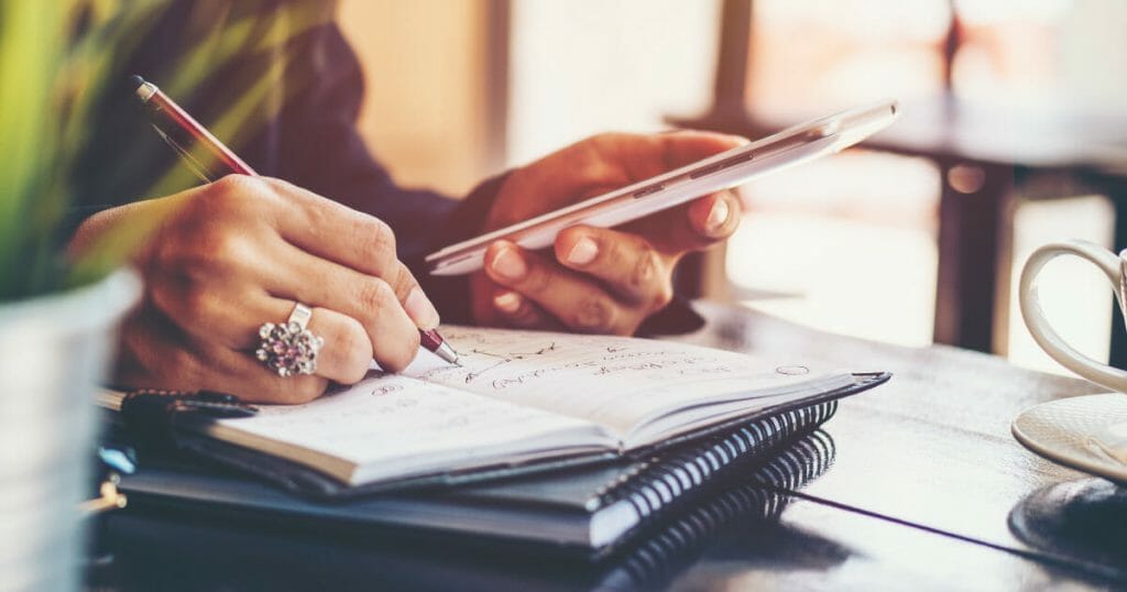 Eine Eventplanerin schreibt eine Checkliste in ihr Notizbuch.