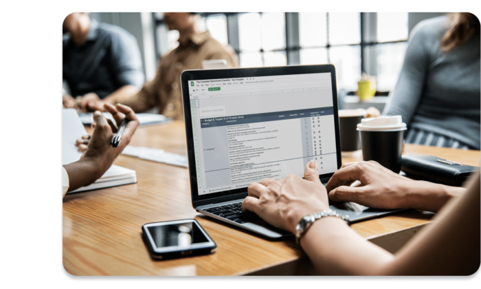 A woman at a conference table with her colleagues using the EventMobi Hybrid Checklist to plan a hybrid meeting.