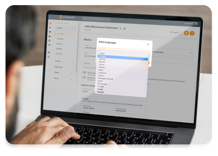 A man using his laptop to check the available languages from the backend of the registration website.
