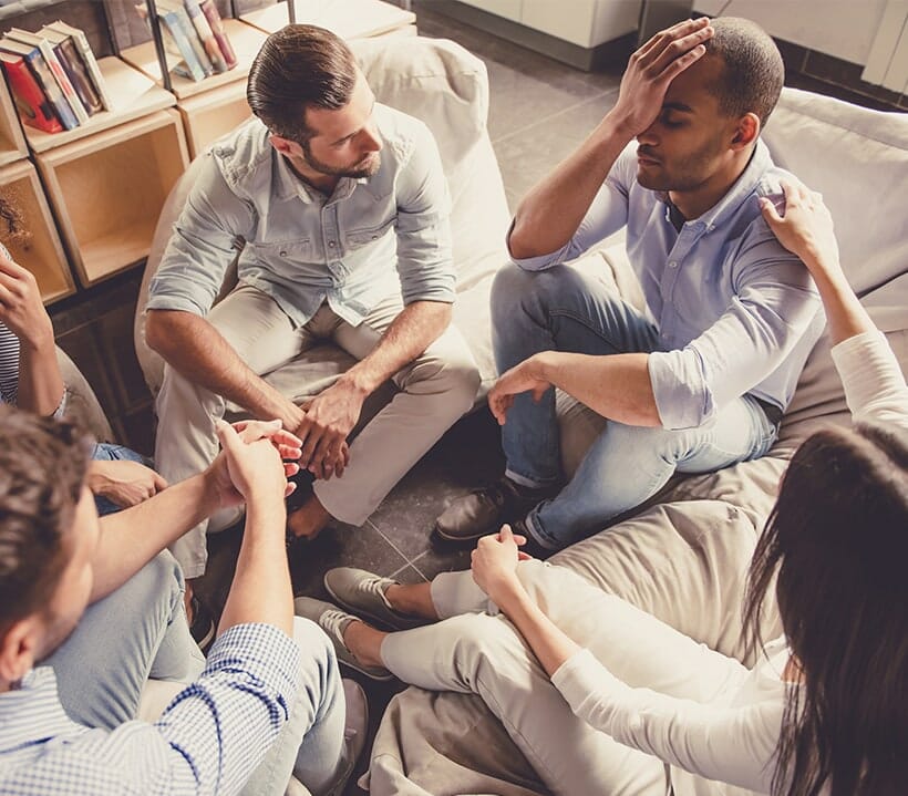 A group of friends consoling their male friend.