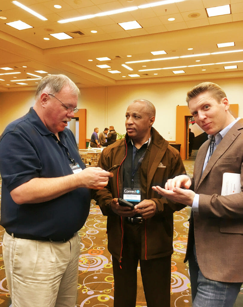 3 RPM Annual National Conference attendees looking at their phones and talking to each other