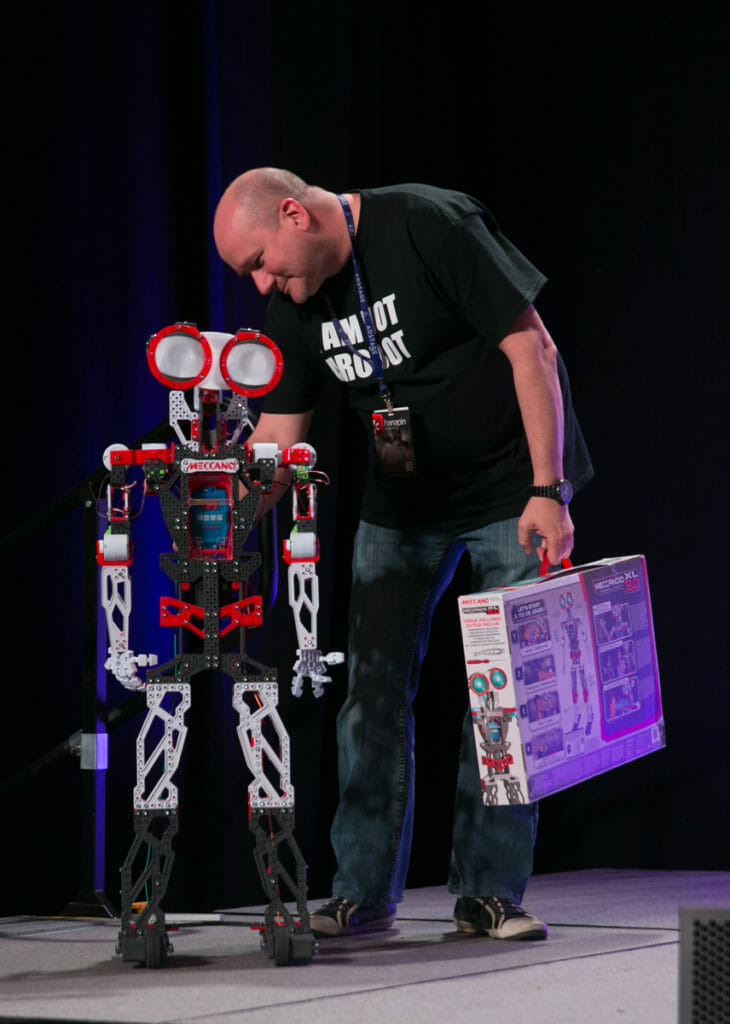 A presenter at Hero Conf on stage alongside a robot.