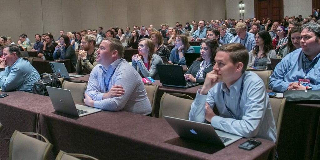 Attendees at Her Conf sitting in rows and attentively listening to a speaker.