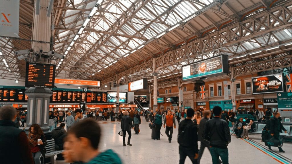 In einer Bahnhofshalle sind verschiedene Arten digitaler Beschilderung angebacht: Werbedisplays, aktuelle Informationen zur Ankunft und Abfahrt von Zügen.