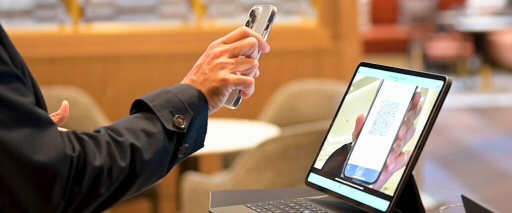 An event attendee holding their phone in front of a laptop to scan their check-in QR code.