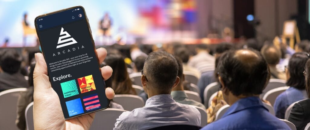 Person, die im Publikum einer Veranstaltung sitzt und ihre Event-App nutzt.