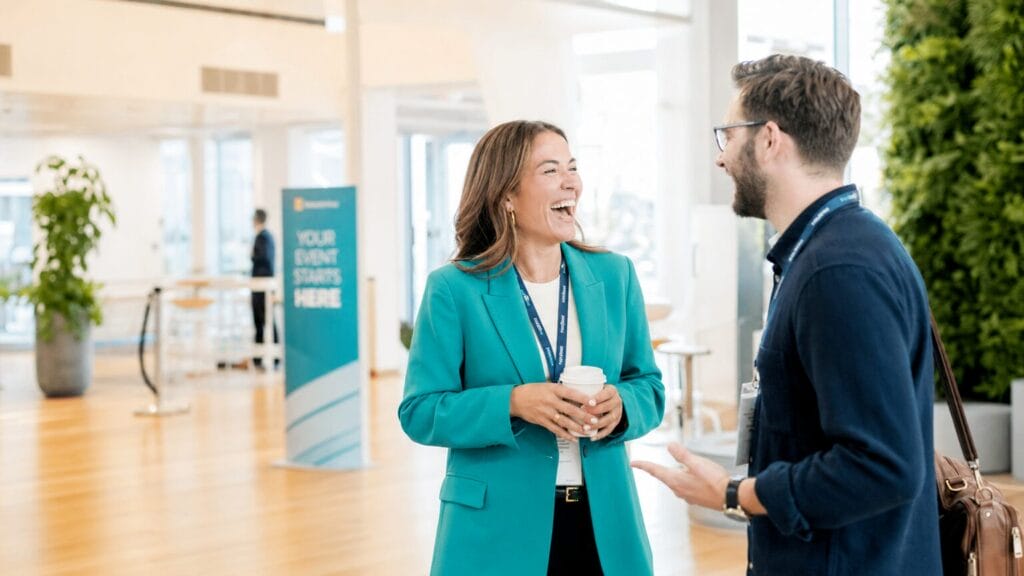 Two conference attendees laughing mid-conversation in a bright, modern event space